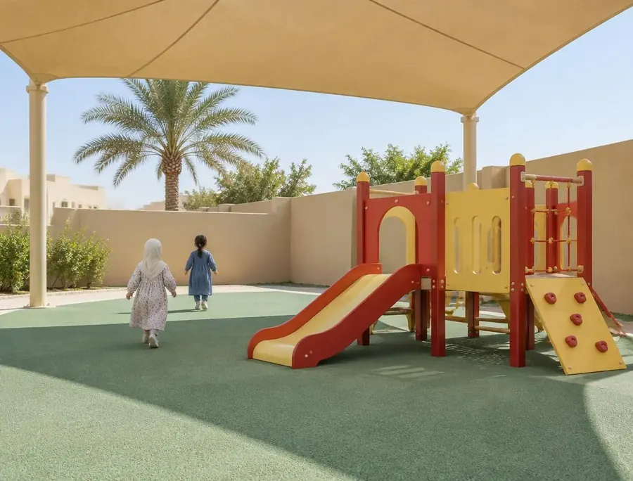 Children seen from behind playing in a shaded outdoor play area with a slide